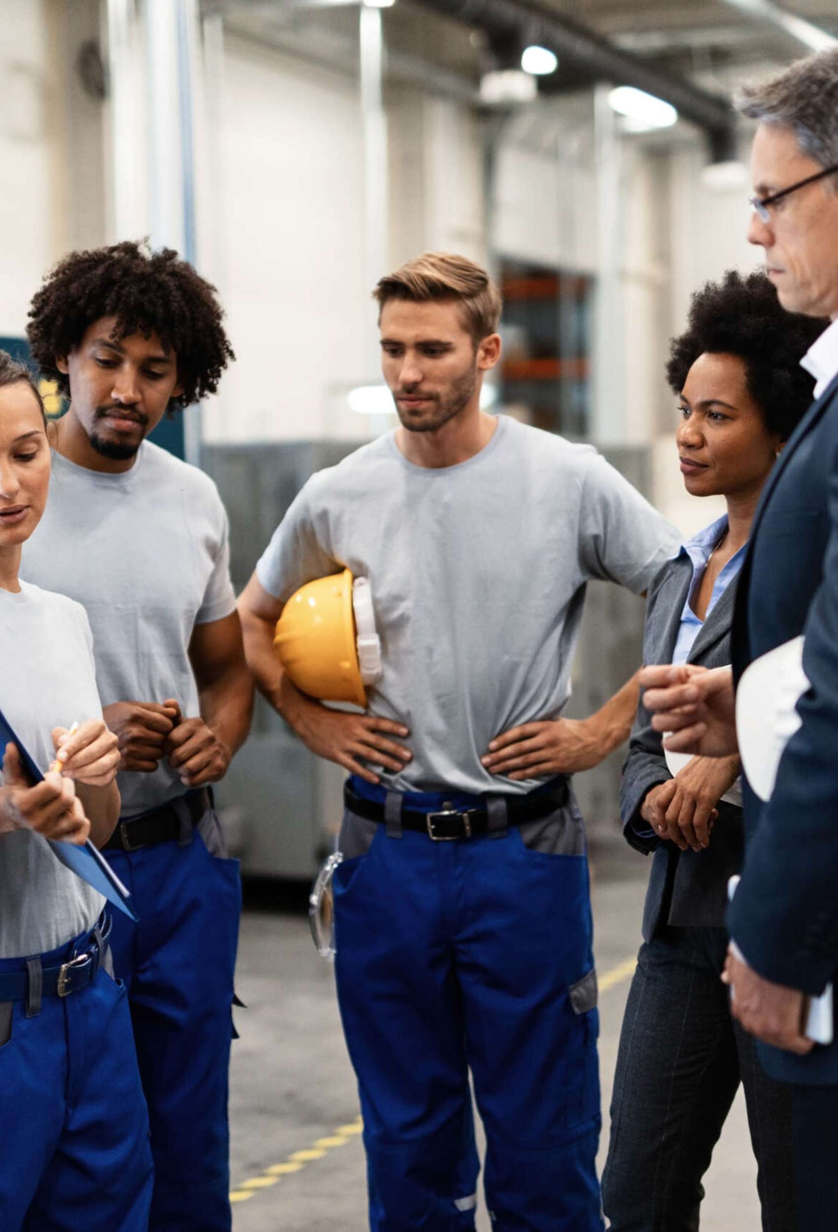 Group of workers having a meeting with company managers in a factory. Focus is on female worker is presenting development reports.